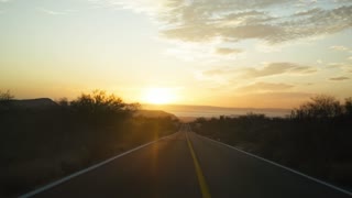 mixkit-two-cars-followed-each-other-on-the-road-at-sunset-50134